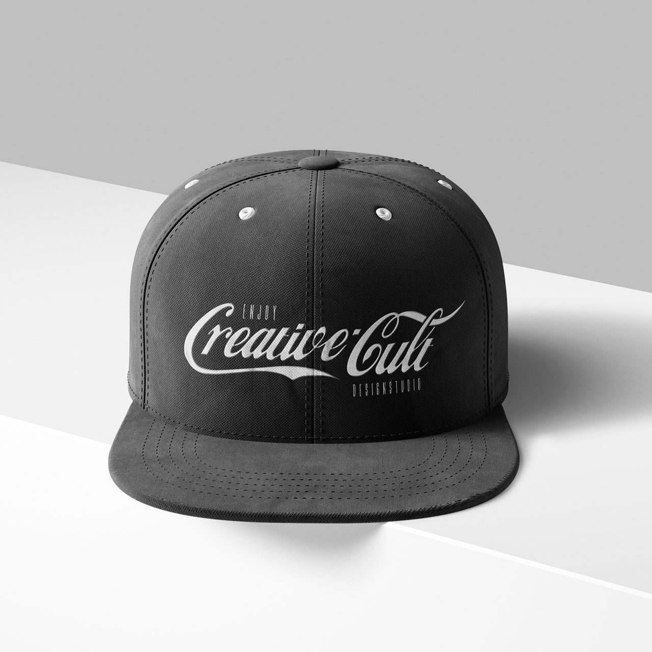 A gray snapback cap with the words "Creative Cult Headwear" in stylized white text on the front, placed against a two-tone gray background.